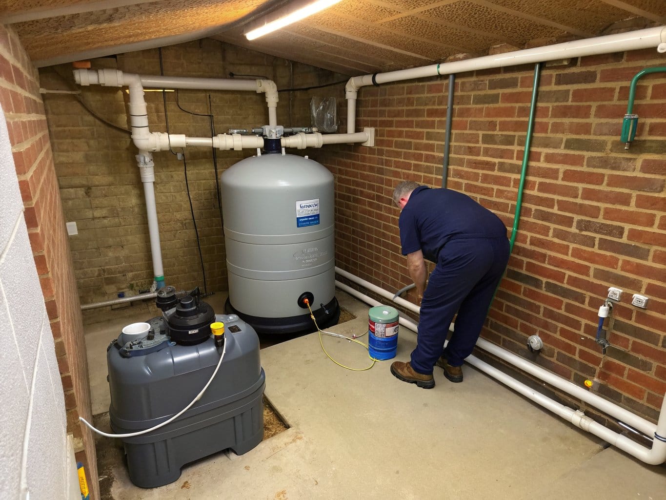 Pool technician draining a sand filter in a plant room while winterising a swimming pool